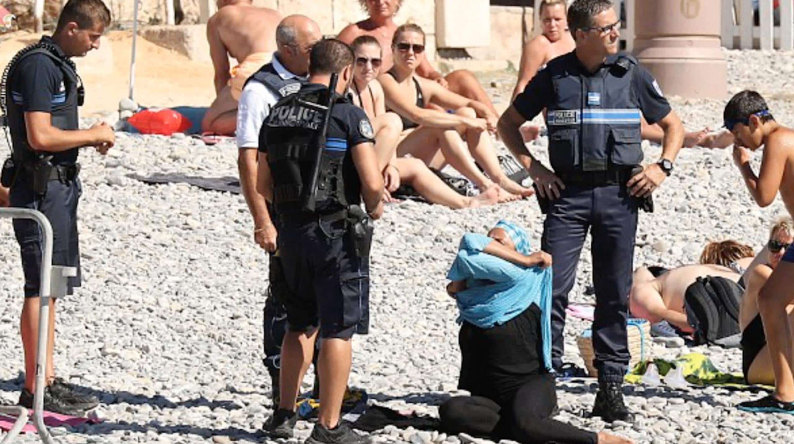 Ligger och solar när fyra poliser tvingar av henne huvudduken