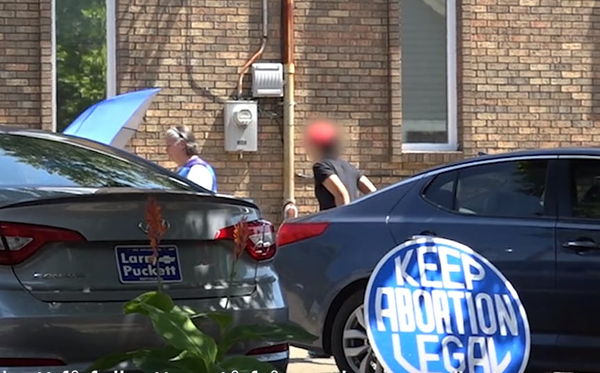 Här eskorteras kvinnorna in – bakom paraplyer