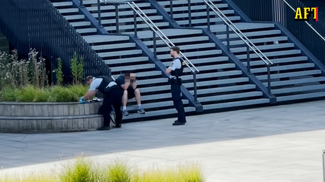 Här tas svensken om hand av polisen efter bombskämtet