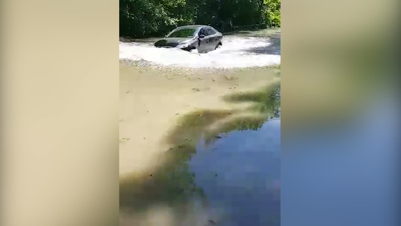 Se bilen försöka köra på den översvämmade vägen