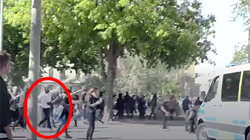 Här syns vitklädde ”hjälten” mota bort stenkastare